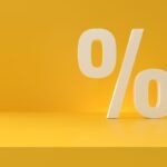 Símbolo de porcentagem em 3D na cor bege sobre fundo amarelo, representando juros, desconto, deságio ou percentual relacionado a finanças, precatórios e RPVs.